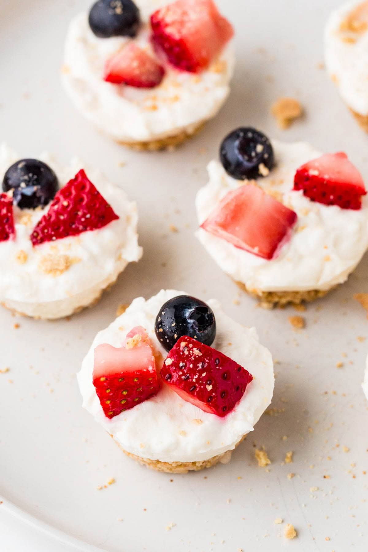 A plate of graham cracker crust mini cheesecakes with fresh berries on top.