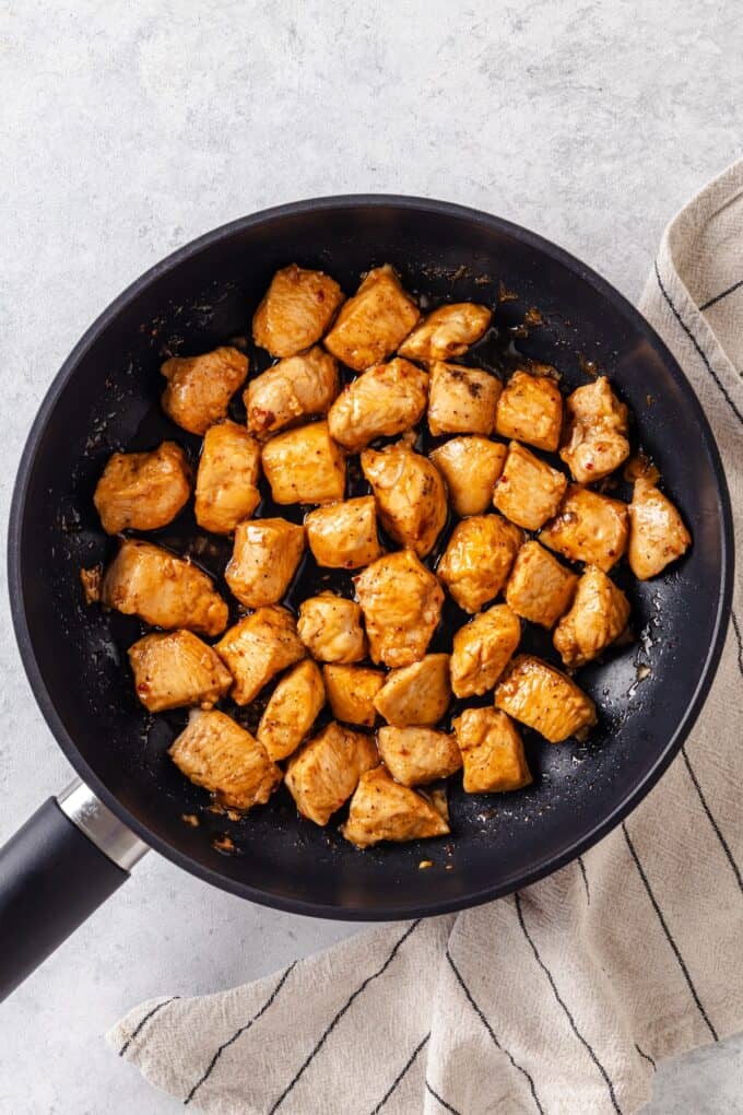 Saucy cooked chicken pieces in a large dark skillet.