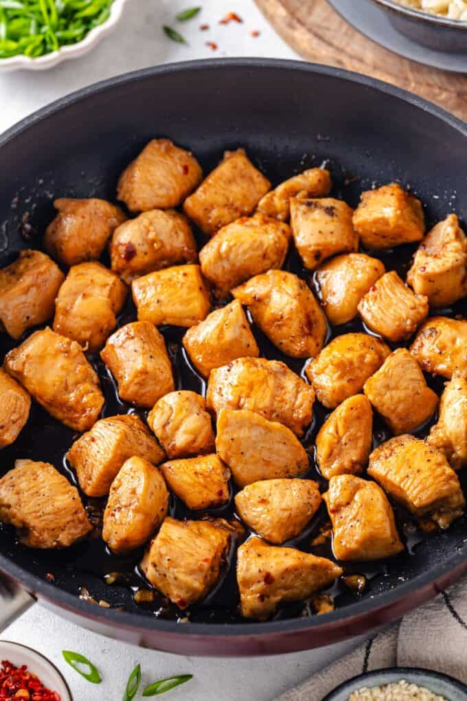 Cooked chicken pieces in a soy sauce mixture in a large dark skillet.