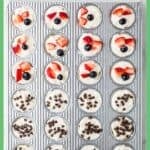 A mini muffin tin with mini cheesecake bites, half topped with fresh berries and half topped with mini chocolate chips with a border and text overlay around the photo.
