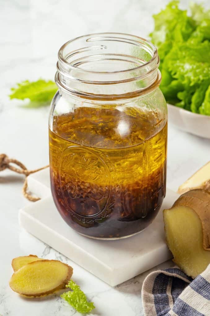 A glass jar with layered vinaigrette ingredients in it before being shaken and mixed.