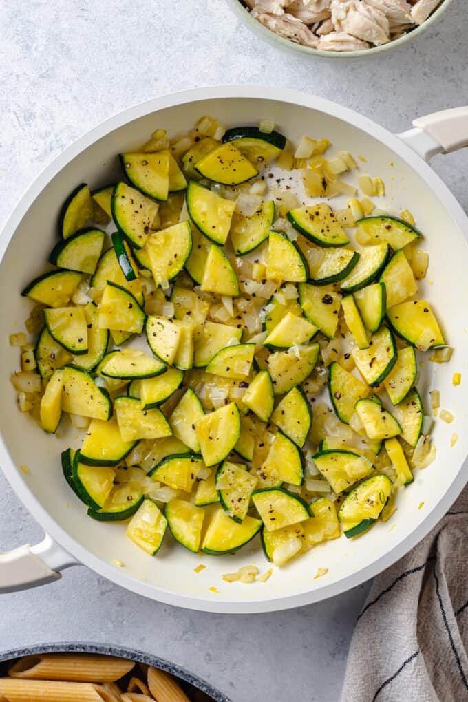 A white skillet with a sautéed mixture of zucchini and onion.