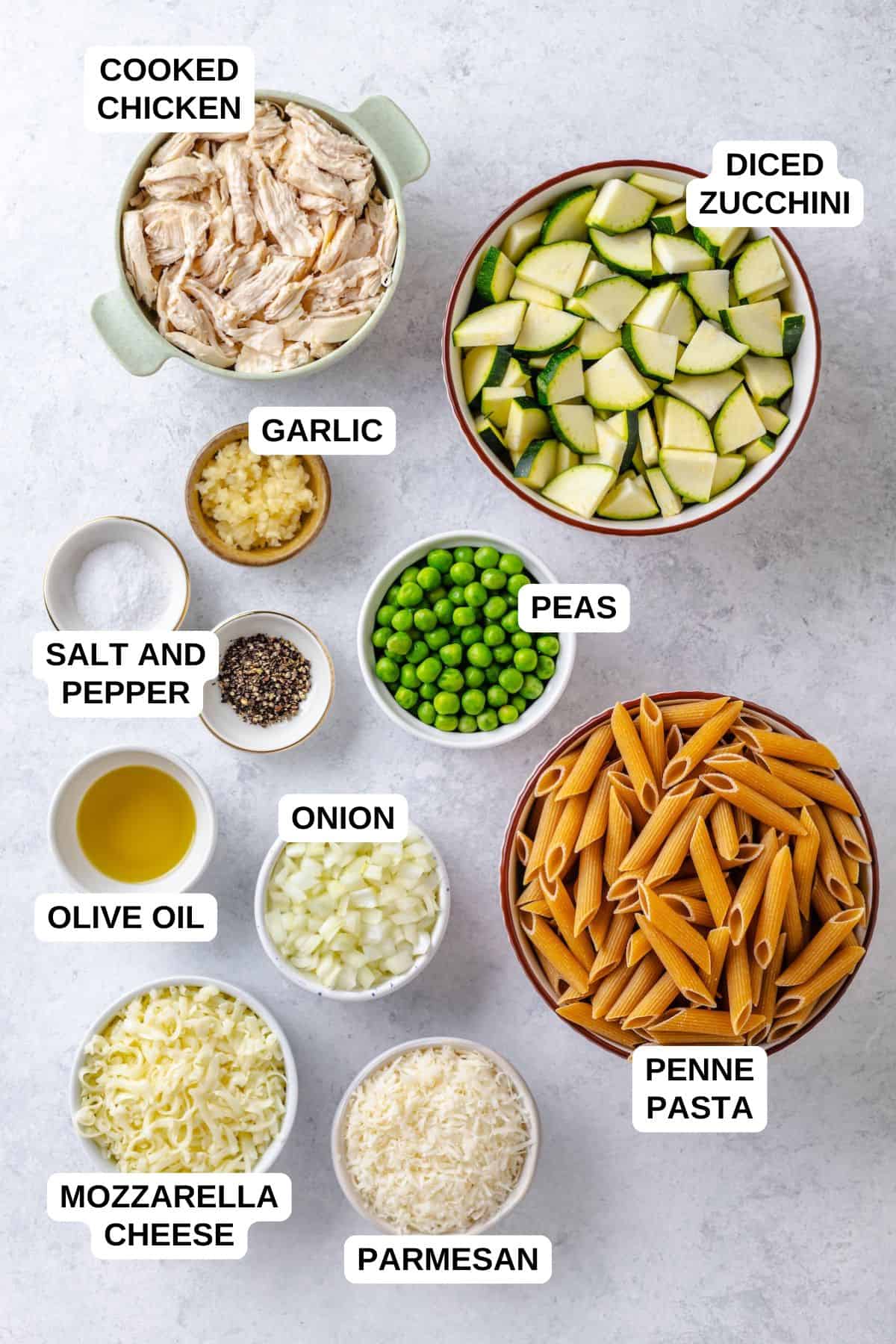 Ingredients laid out in separate bowls for making a chicken and zucchini pasta dish.