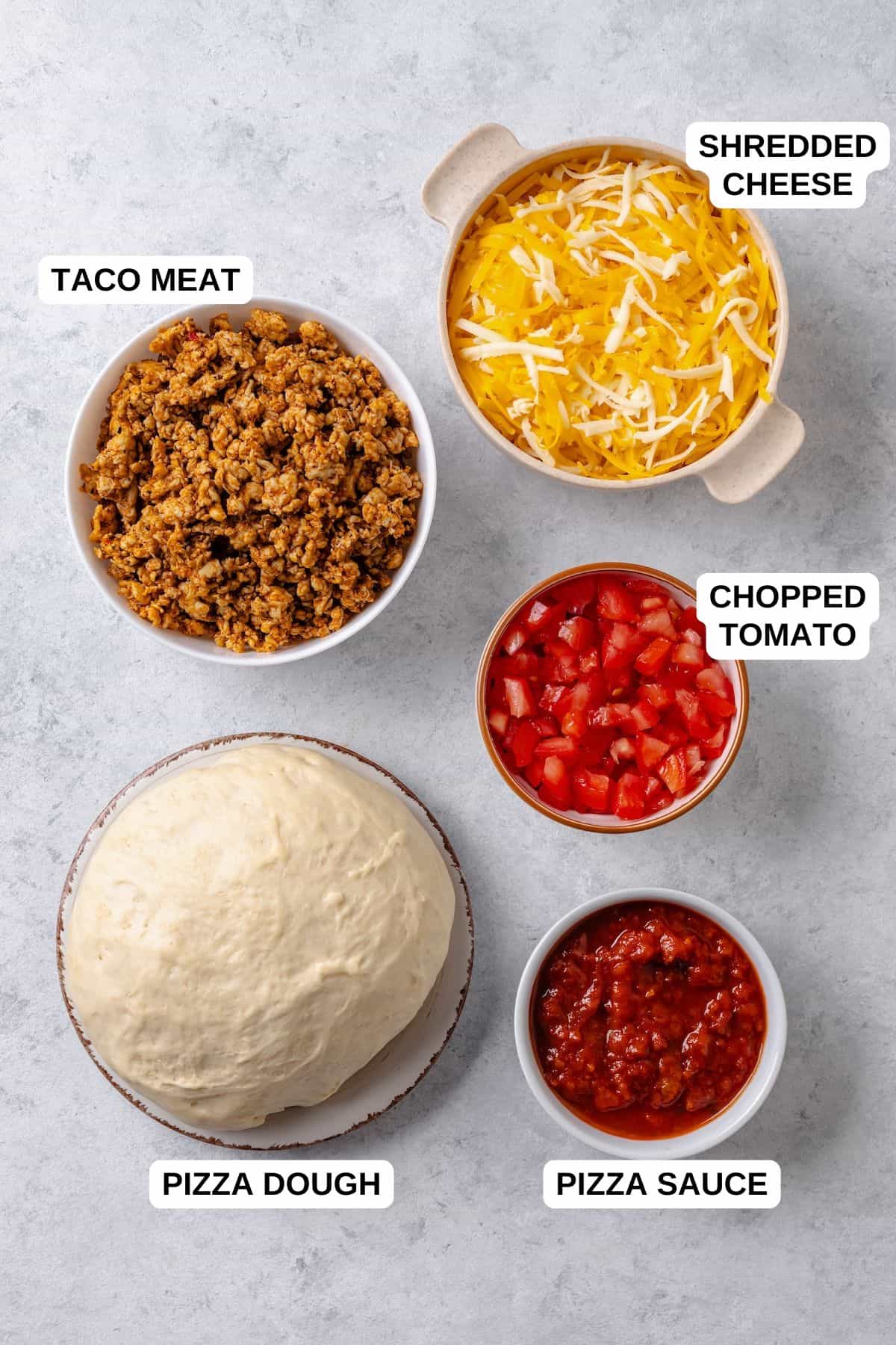 Ingredients laid out in separate containers on a counter for making a homemade taco pizza.