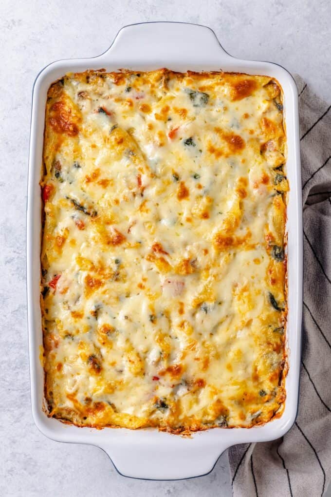 A cheesy chicken and pasta bake in a rectangular casserole dish.