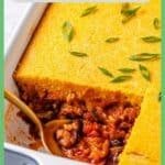 A spoon resting in the corner of a casserole dish with a square piece of chili and cornbread cut out of it with a green border and a text overlay around the photo.