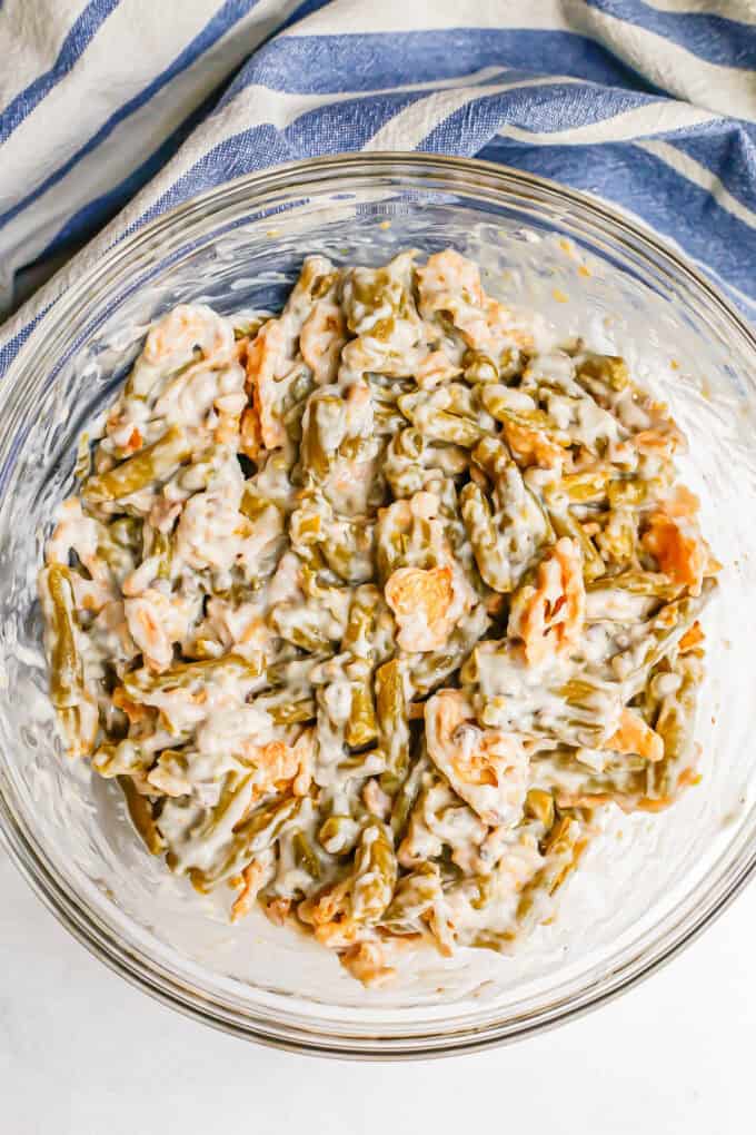 A large glass bowl with a creamy green bean mixture with French fried onions.
