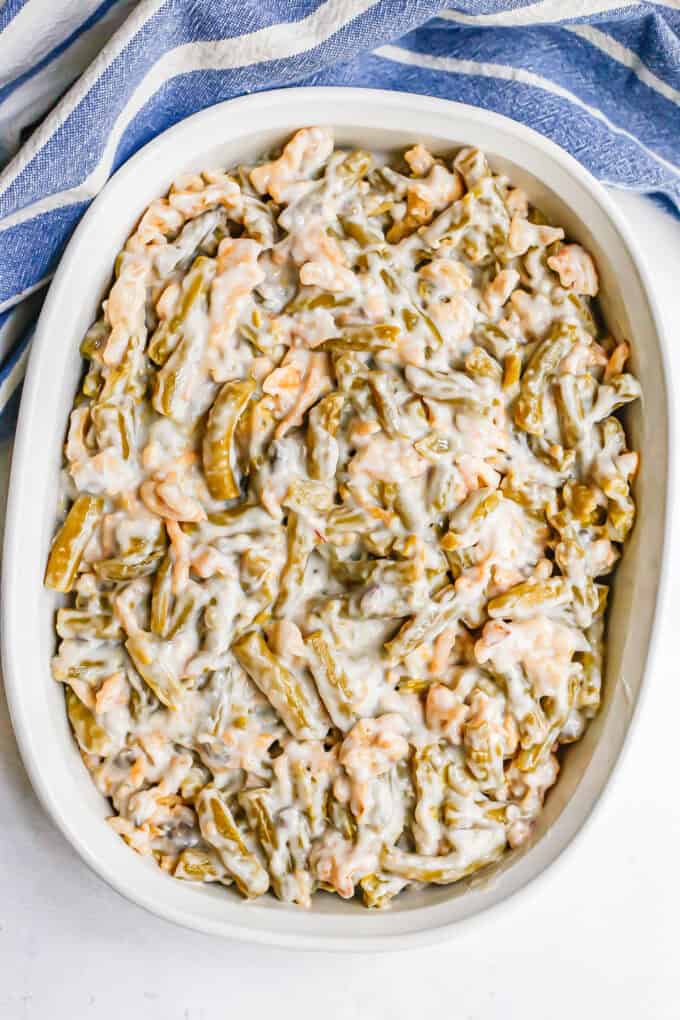 Green bean casserole in a white oval baking dish before being cooked.