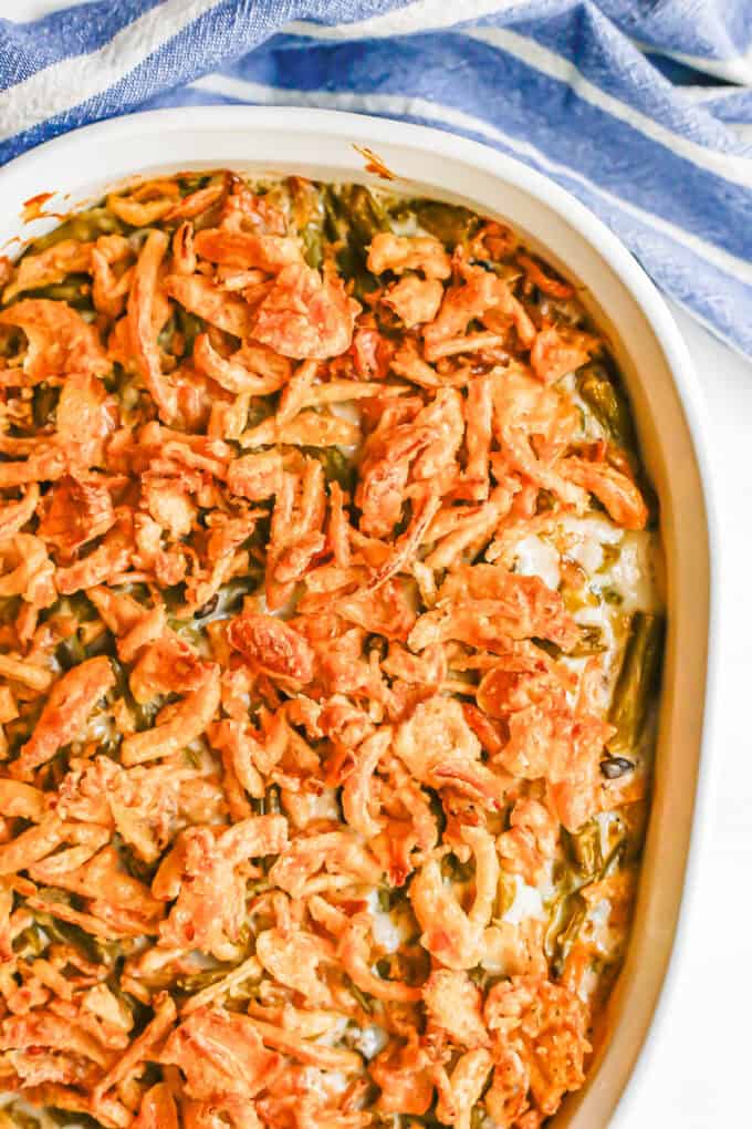 Close up of a green bean casserole in a white dish with French fried onions on top.