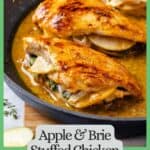 Apple and brie stuffed chicken breasts in a pan sauce in a large dark skillet with a border and text around the photo.