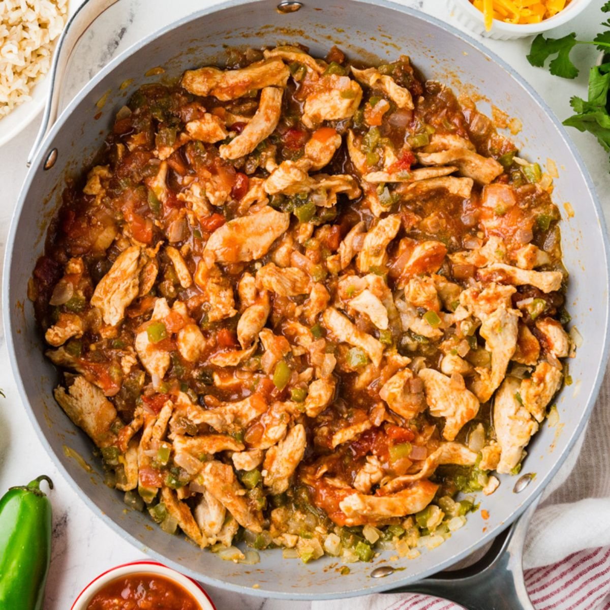 Close up of a skillet of a salsa chicken with peppers and onion mixture.