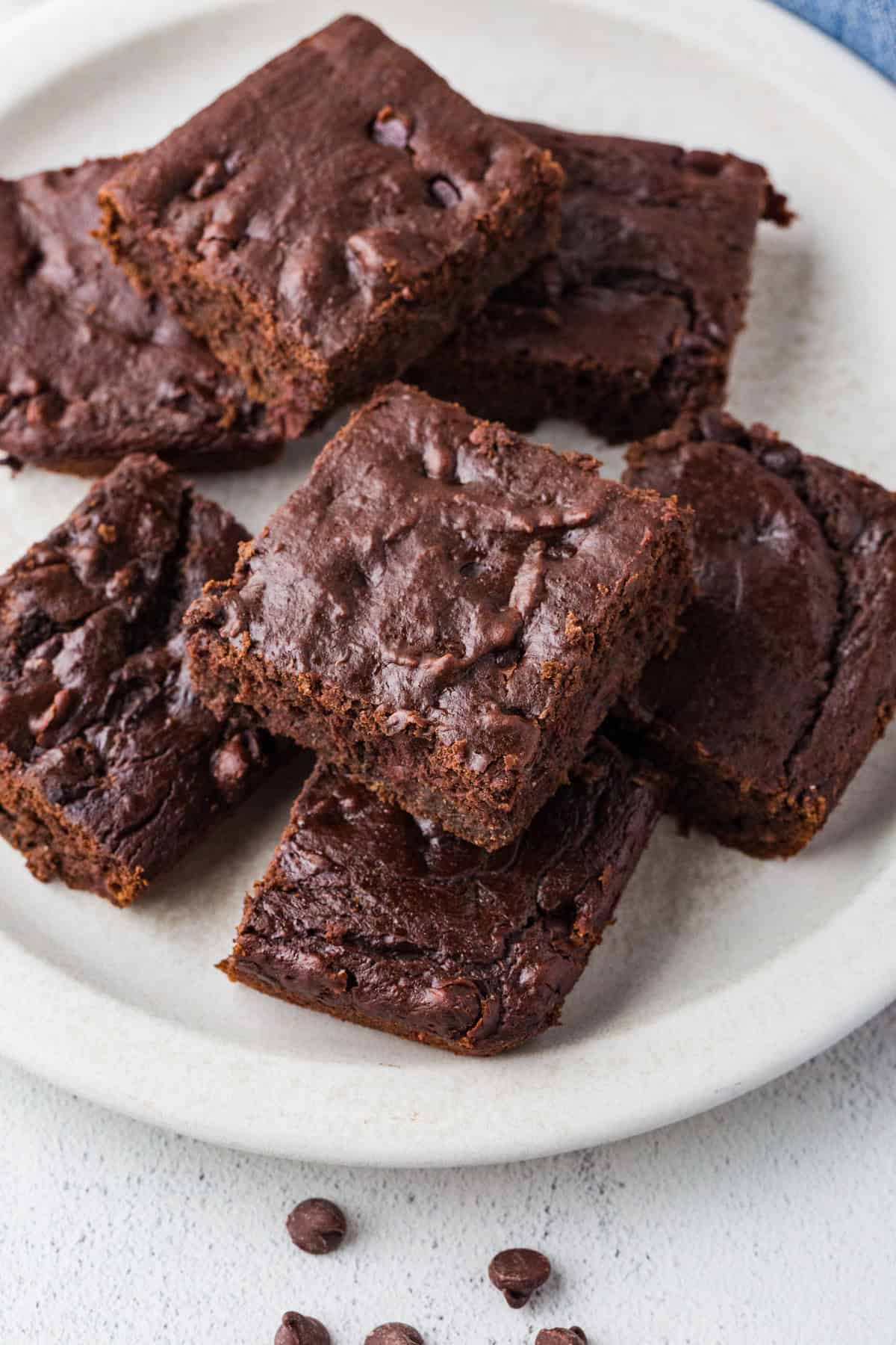 A plate full of square cut slices of chocolate pumpkin cake with chocolate chips.