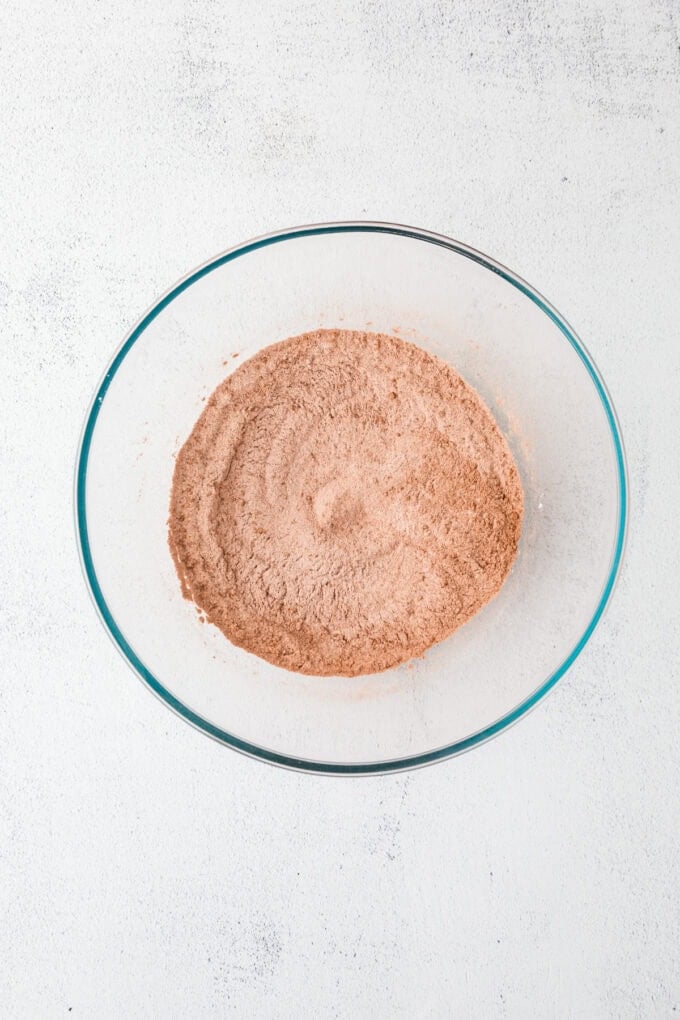 A clear glass bowl with a flour, sugar and cocoa powder mixture.