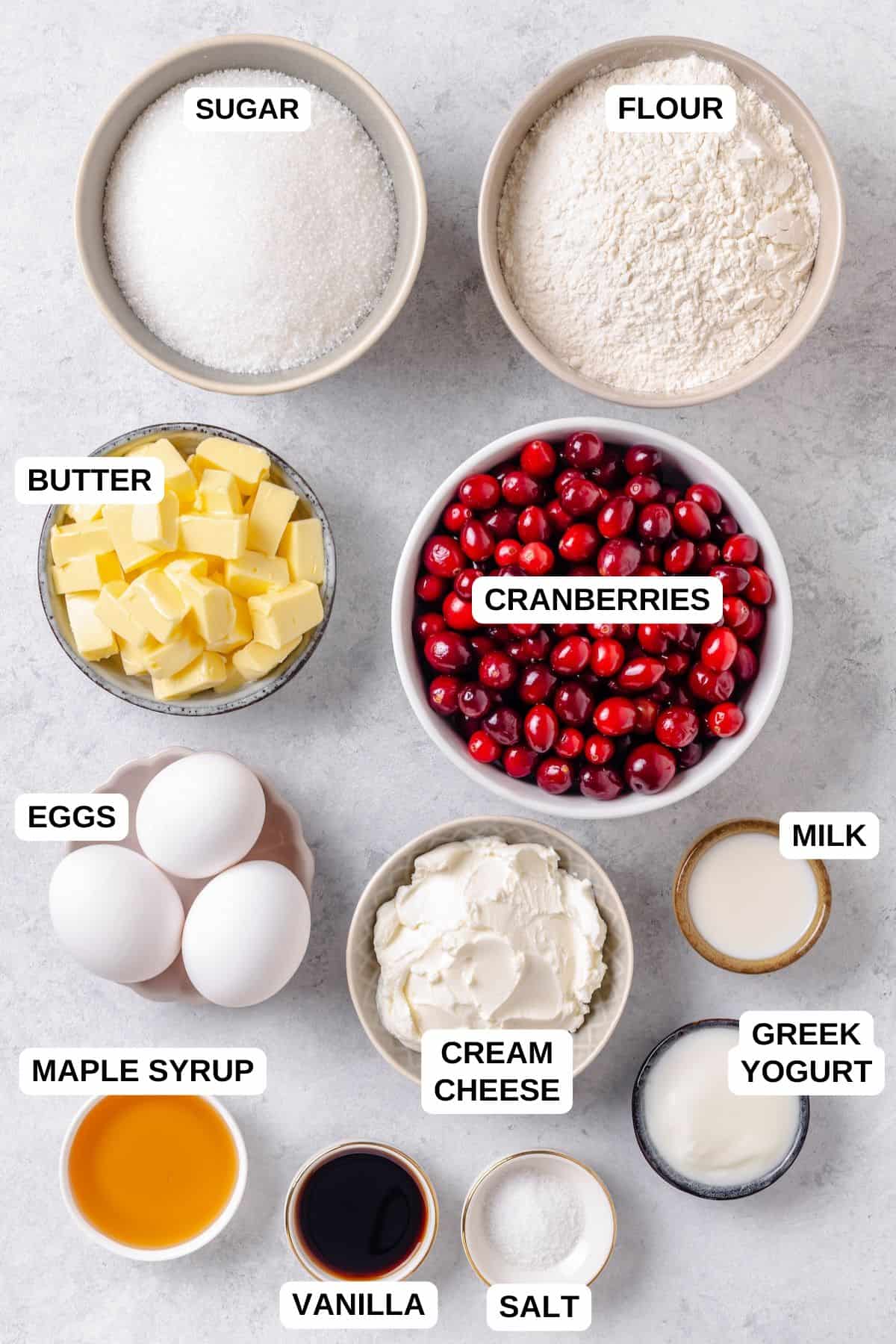 Ingredients laid out in separate bowls for making a cake with fresh cranberries and a cream cheese frosting.