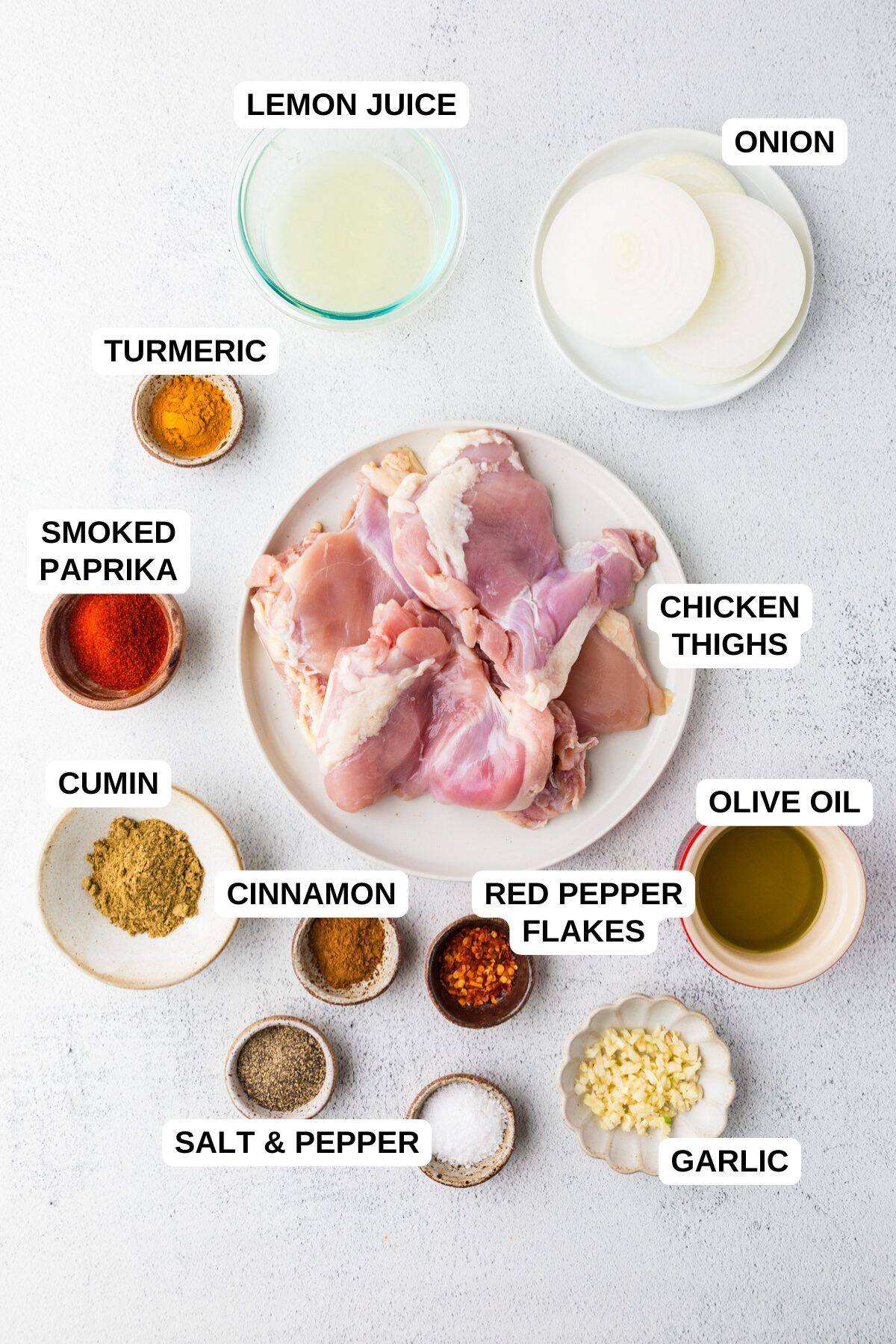 Ingredients laid out in separate bowls for making a chicken thigh recipe with onions and seasonings.