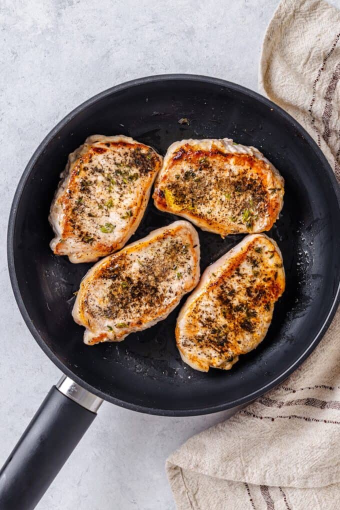 Seared pork chops in a skillet.