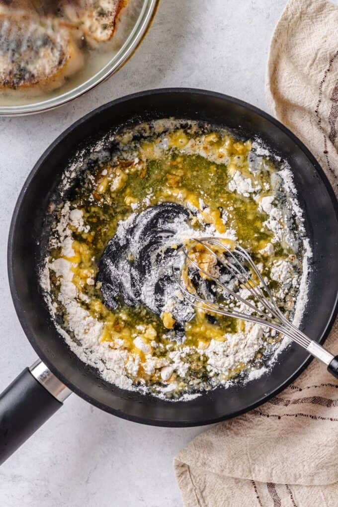 Butter and flour being whisked together in a skillet.