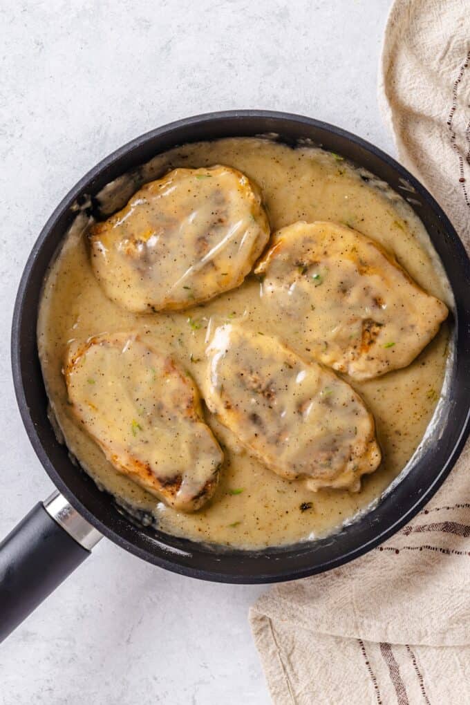Gravy coated pork chops in a skillet.