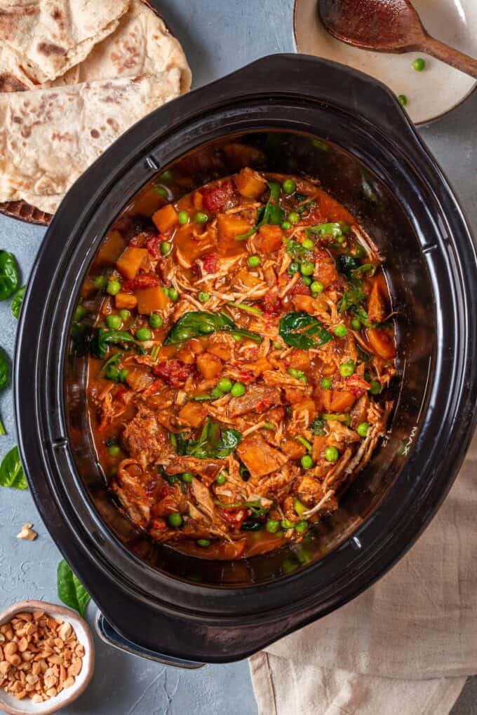Chicken curry with sweet potatoes, peas and spinach in a slow cooker after being cooked.