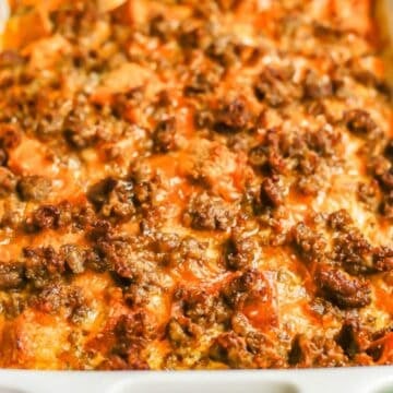 Close up of a cheesy baked sausage and egg casserole in a white baking dish.