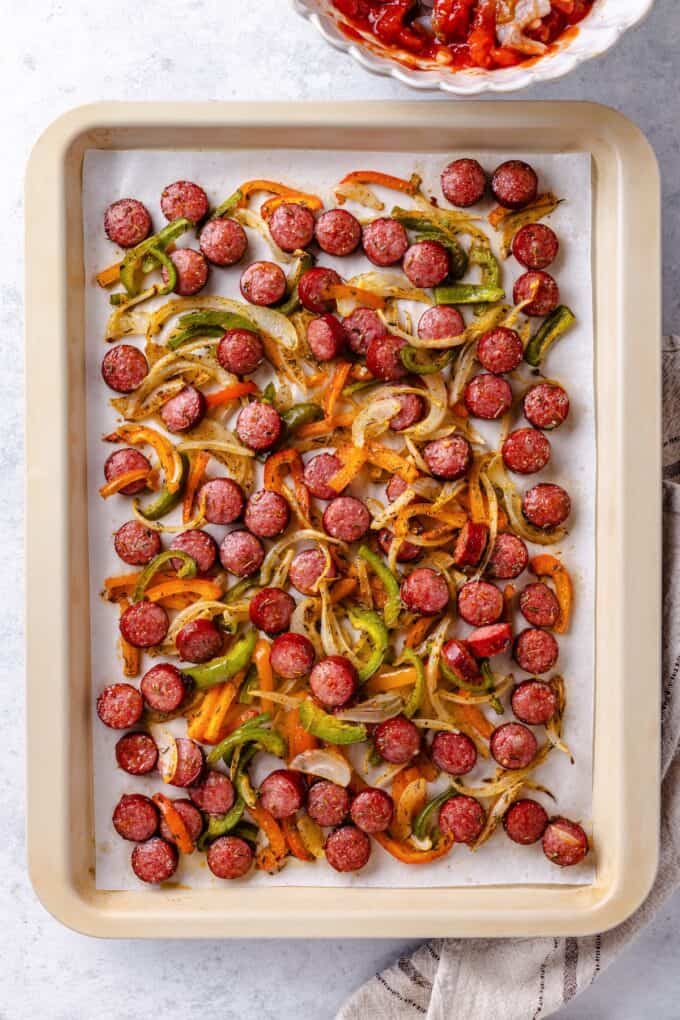 A mix of roasted andouille sausage and peppers and onions on a sheet pan.