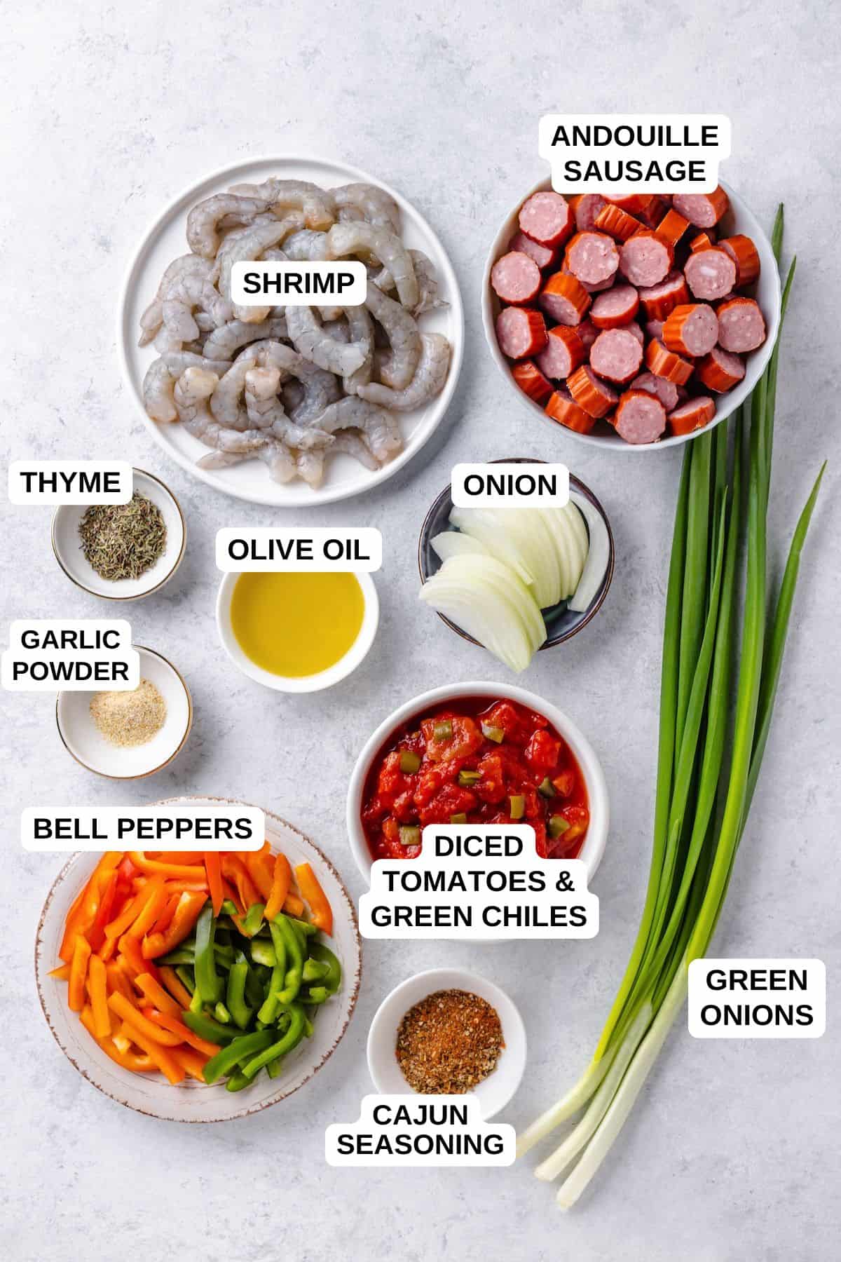 Ingredients laid out in separate bowls for making a jambalaya recipe with shrimp and andouille sausage.