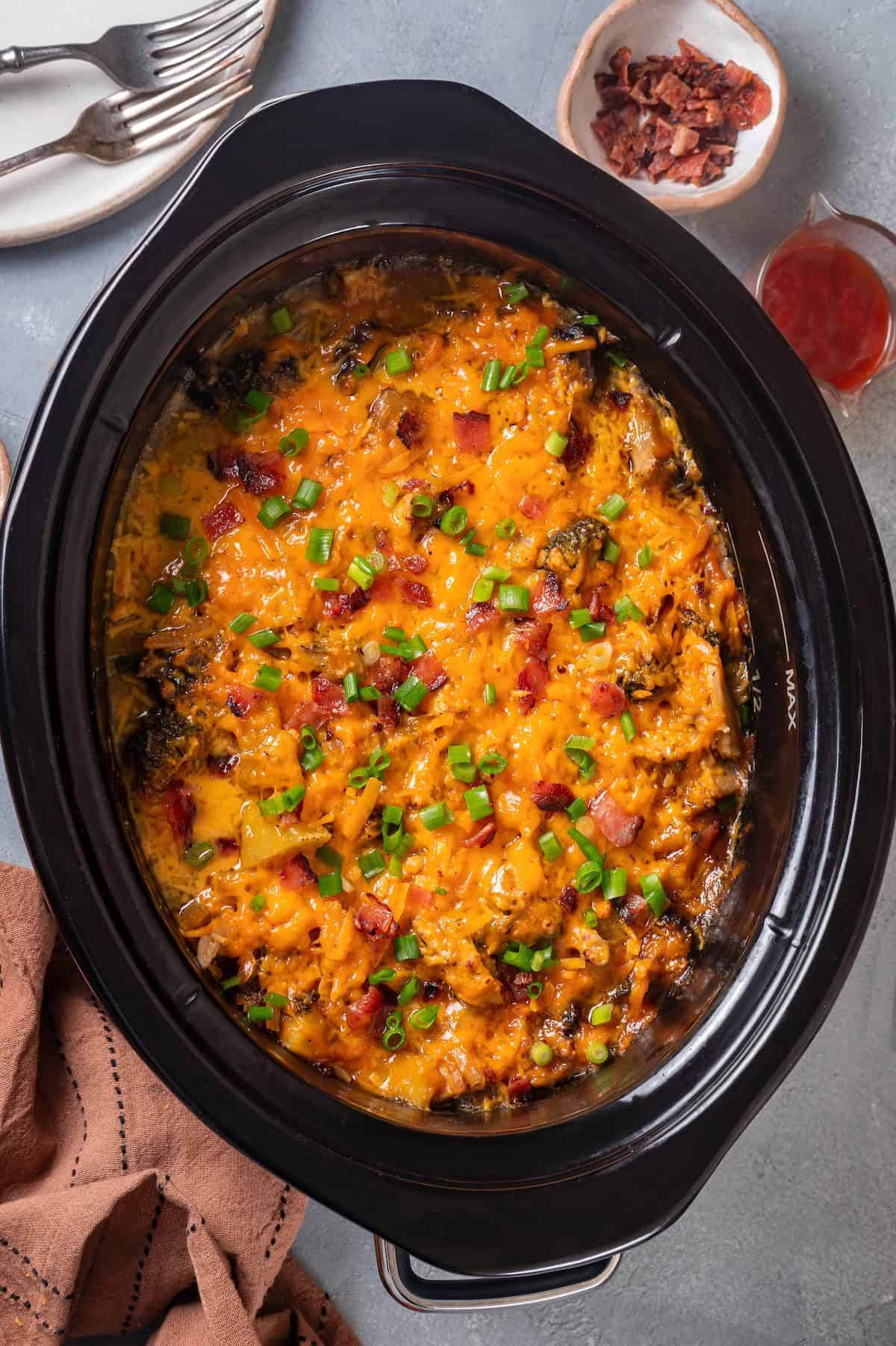 A cheesy slow cooker chicken casserole with bacon and green onions on top.