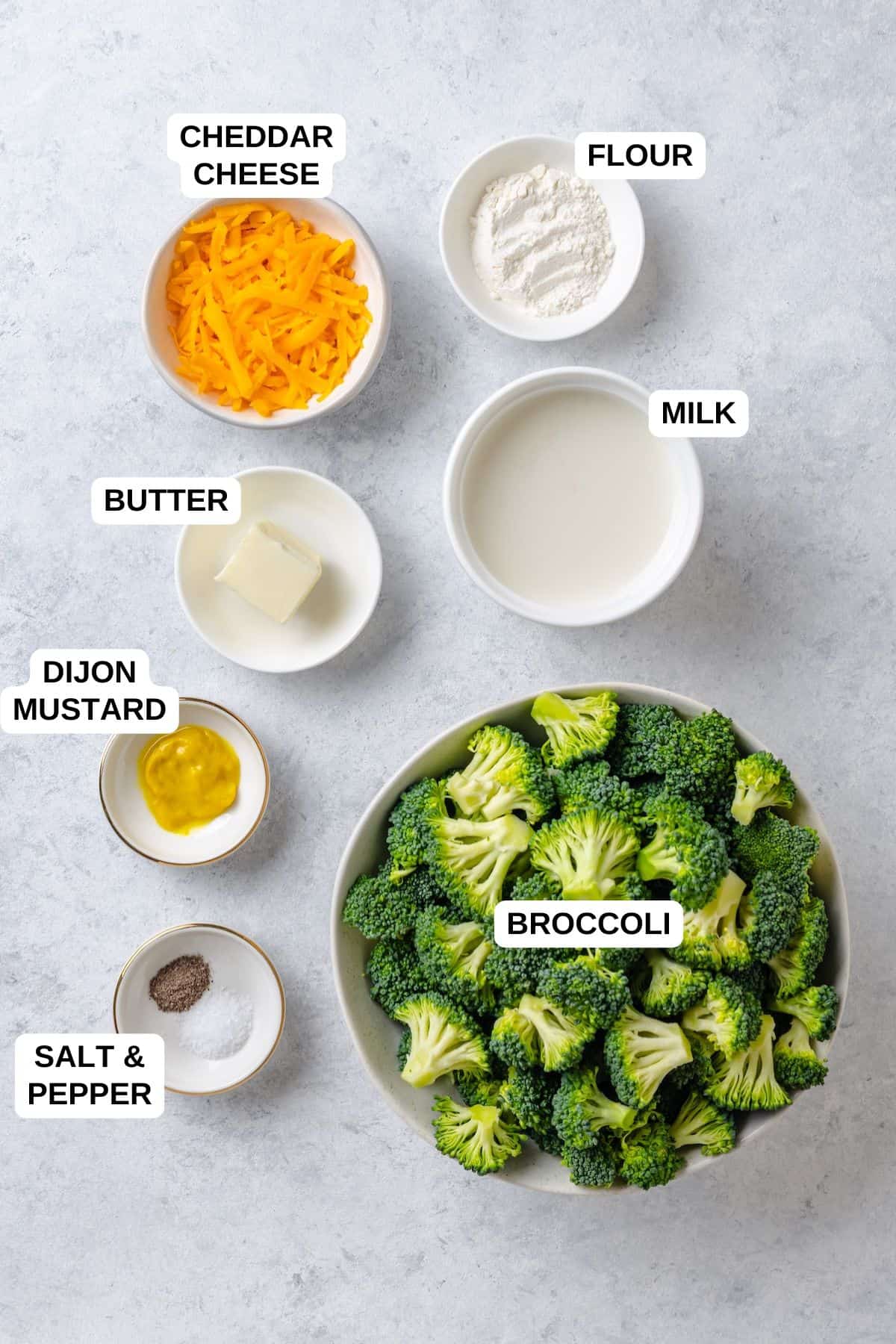 Ingredients laid out in separate bowls for making a broccoli recipe with a cheddar cheese sauce.