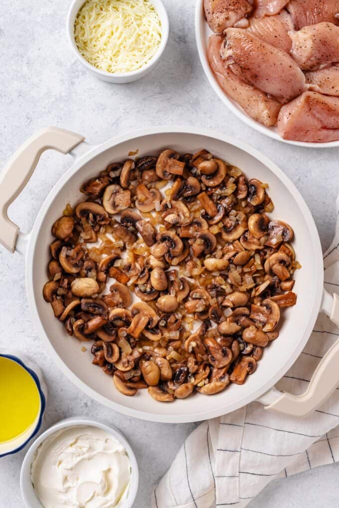 Sautéed onions and mushrooms in a large white skillet.