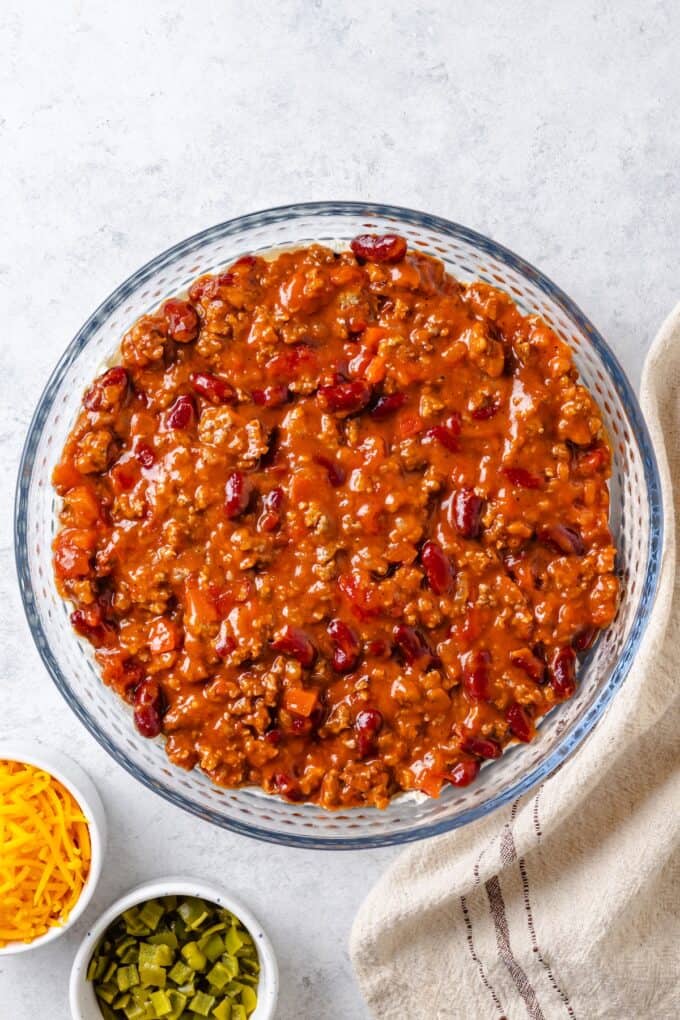 A can of prepared chili spread over a layer of cream cheese in a glass pie plate.