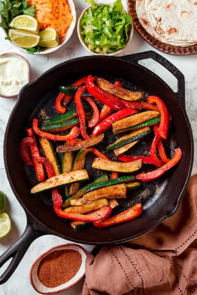 Sautéed zucchini and red bell pepper in a cast iron skillet.