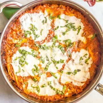 Close up of a large skillet with a shortcut easy lasagna topped with melted fresh mozzarella cheese and fresh basil.