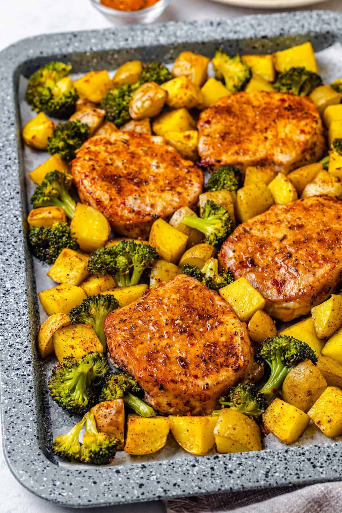 Boneless pork chops cooked on a sheet pan alongside roasted potatoes and broccoli.