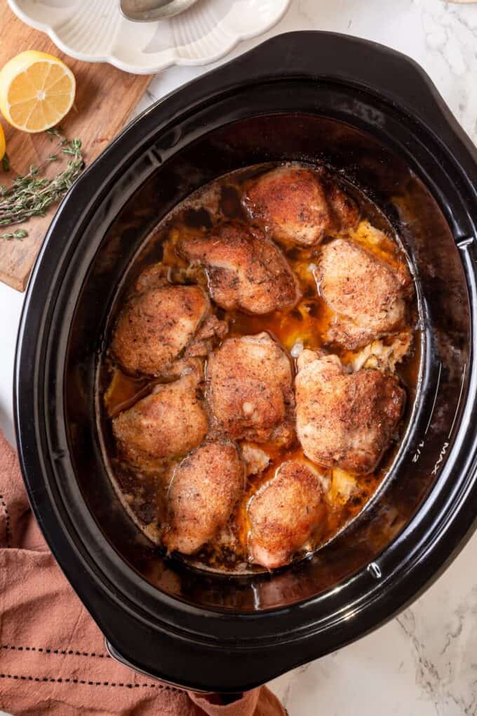 Cooked chicken thighs in a slow cooker.