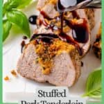 Balsamic glaze being poured over sliced stuffed pork tenderloin on a serving tray with fresh basil to the side and a green border and text around the photo.