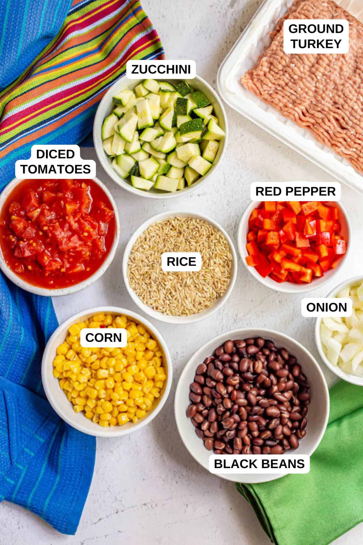 Ingredients laid out in separate bowls for making a ground turkey and rice recipe with black beans, corn and veggies.
