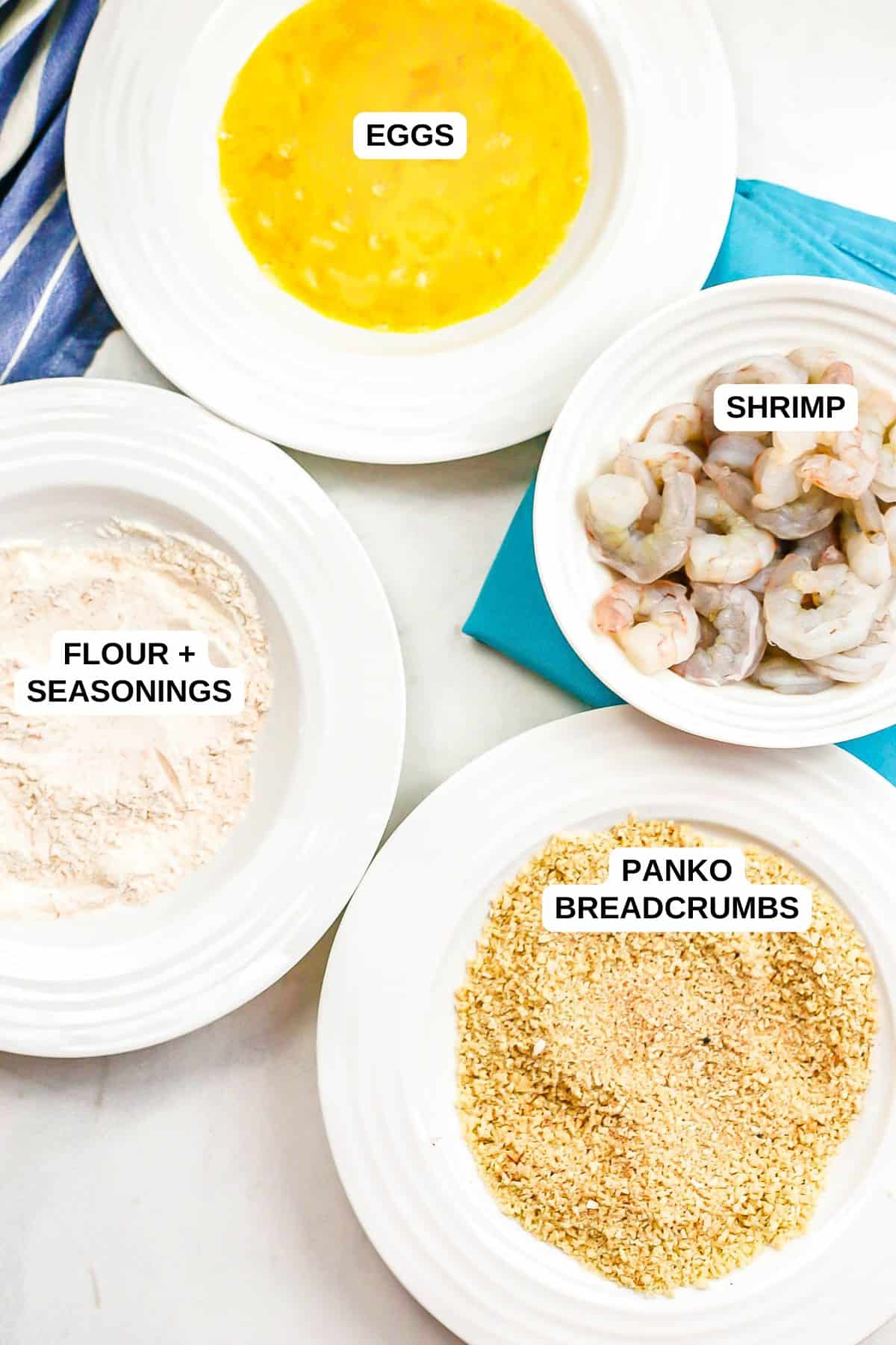 Ingredients laid out in separate bowls for making a breaded shrimp recipe.