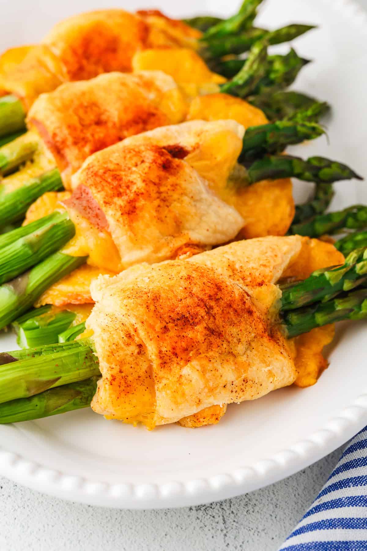 A serving plate with four asparagus rolls lined up.