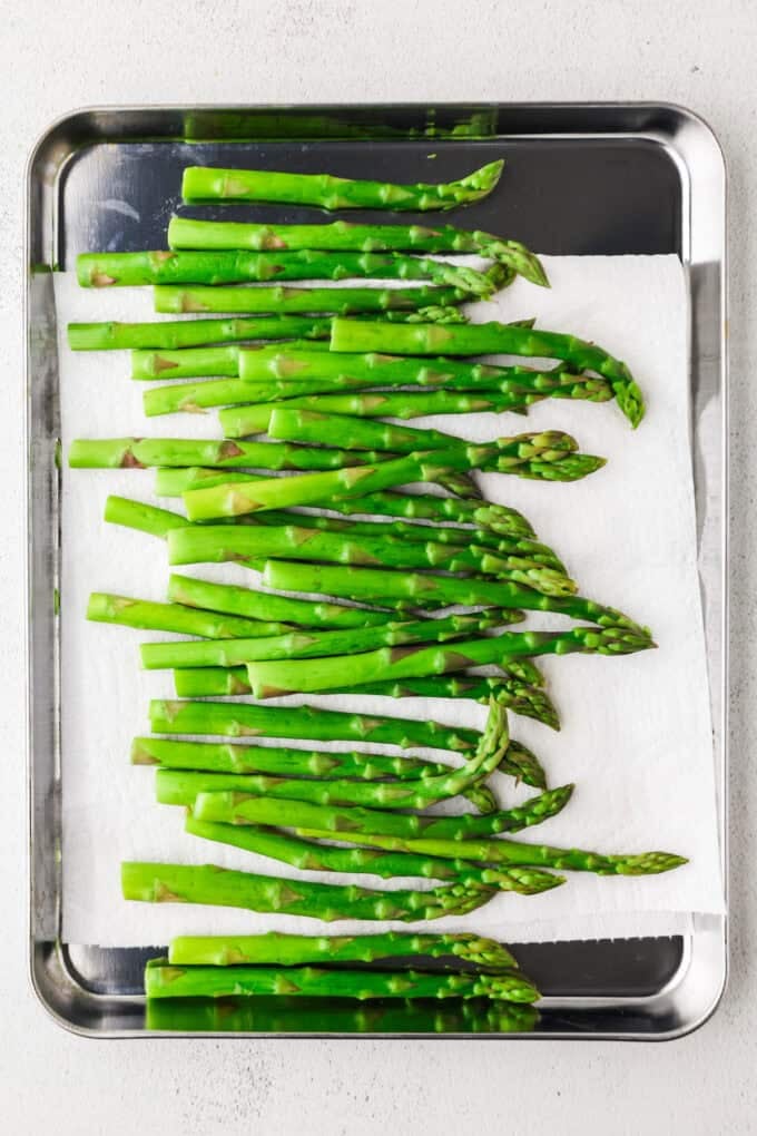 A sheet pan full of washed and blanched asparagus spears.