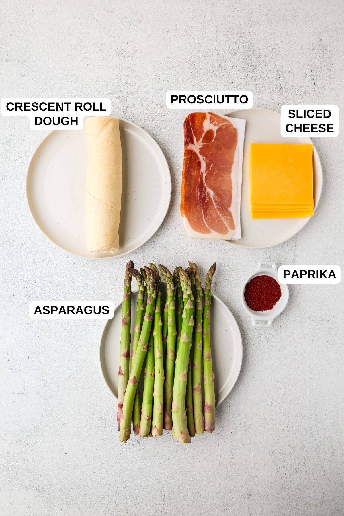 Ingredients laid out on separate small plates for making an asparagus recipe with cheese and prosciutto.