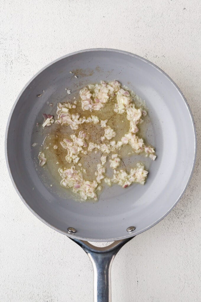 A skillet with diced shallots sautéing in butter.