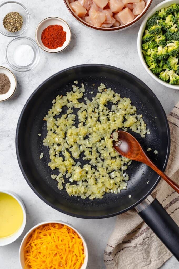 Sautéed onion in a skillet with a wooden spoon resting in it.
