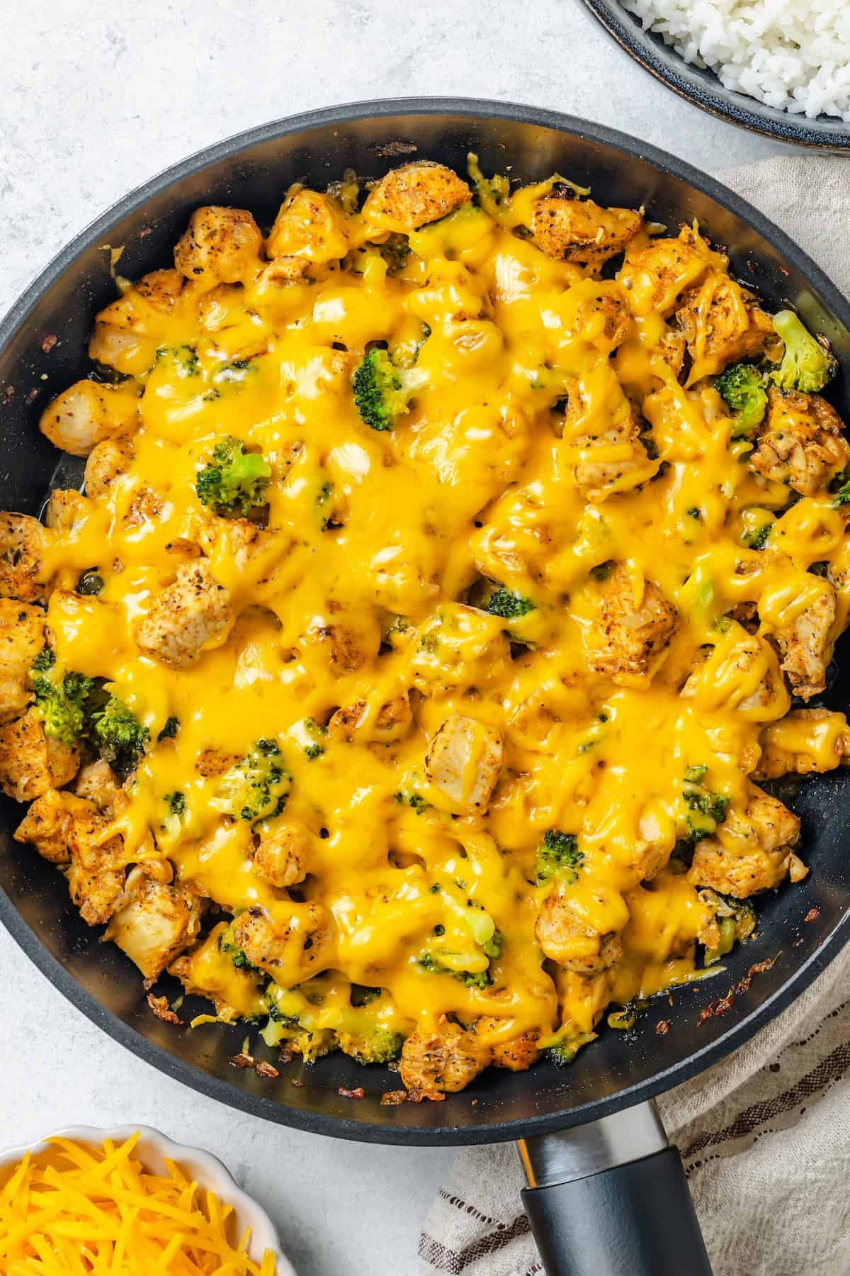 Overhead of a large dark skillet full of a cheesy chicken and broccoli dish.