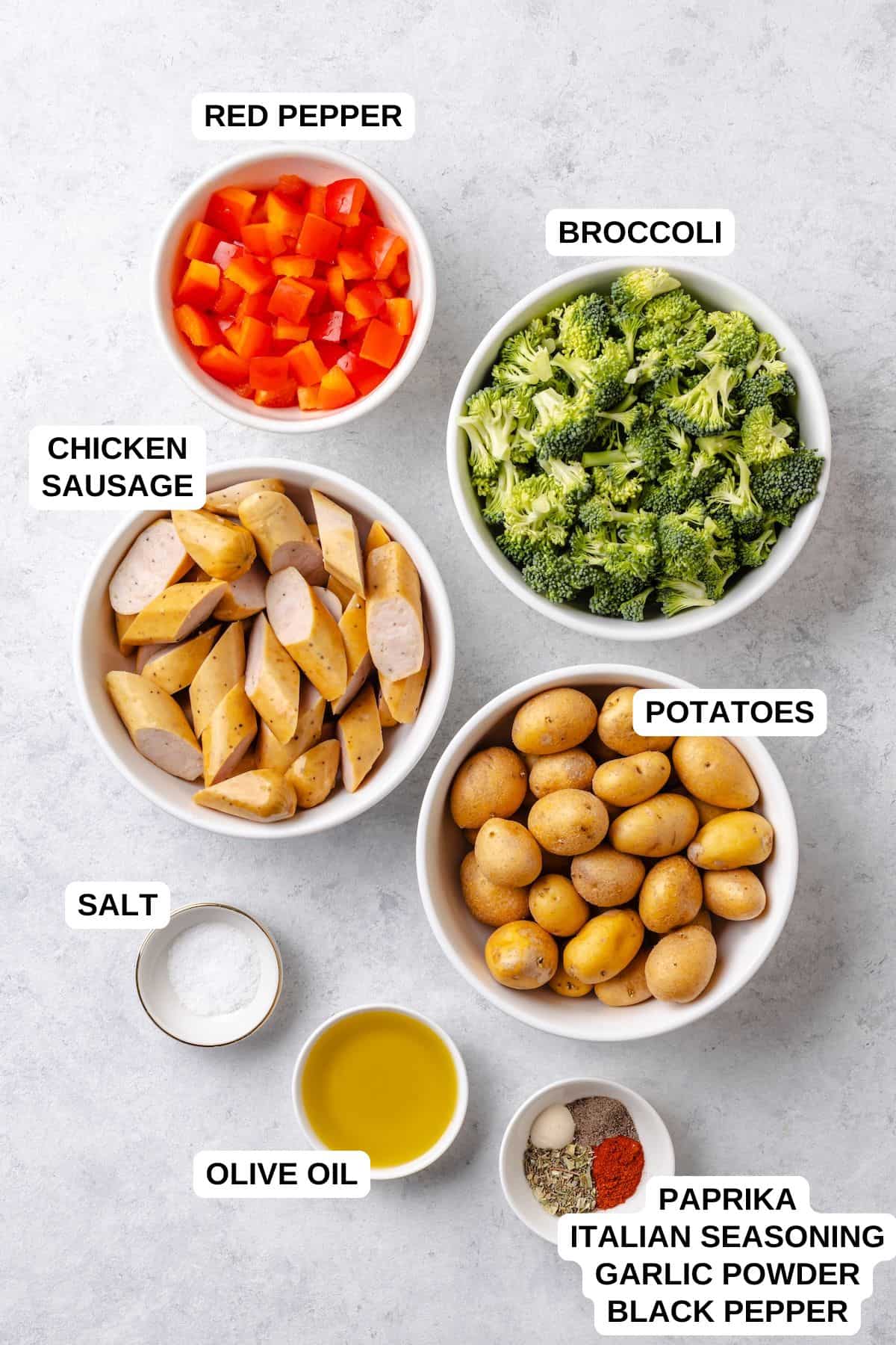 Ingredients laid out in separate bowls for making a chicken sausage recipe with potatoes and broccoli.