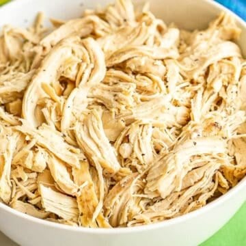 Close up of shredded chicken in a white bowl.