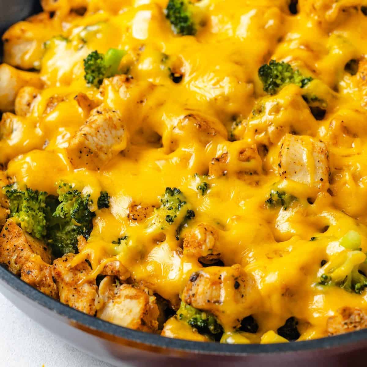Close up of a large dark skillet filled with a cheesy chicken and broccoli mixture.