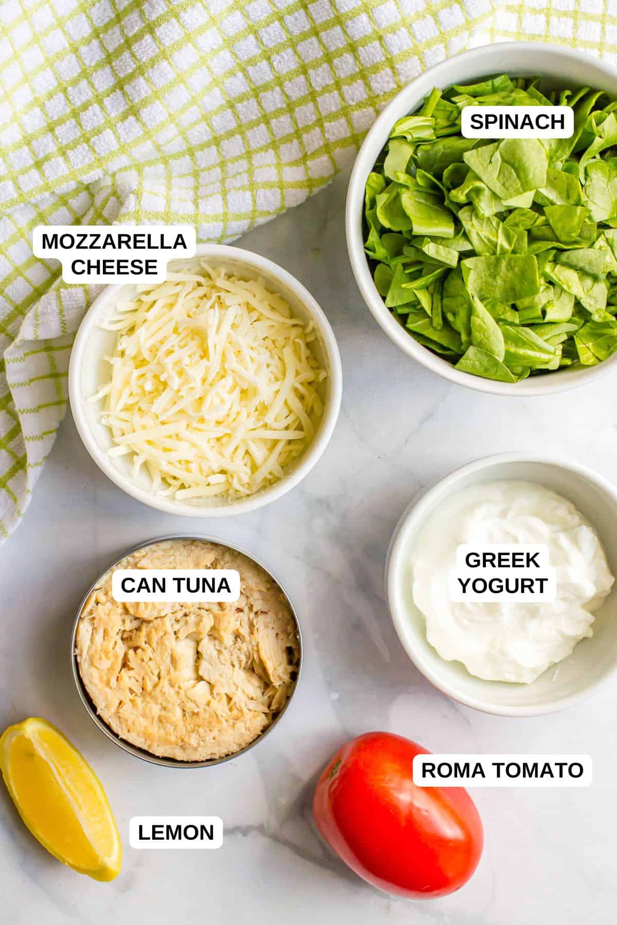 Ingredients laid out in separate bowls for making a healthy tuna salad recipe with spinach, tomato and mozzarella cheese.