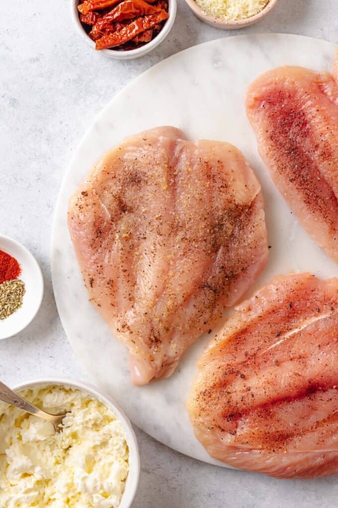 Butterflied and seasoned chicken breasts on a plate.