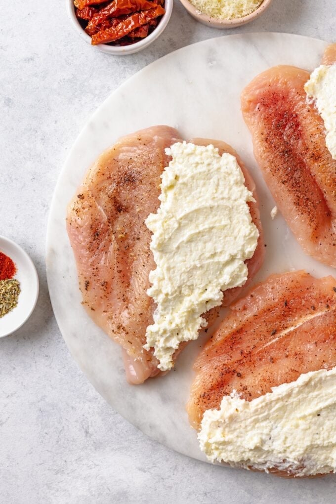 A cream cheese mixture spread on one side of butterflied chicken breasts.