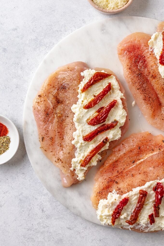 Sun dried tomatoes placed on top of a cream cheese mixture spread on one side of butterflied chicken breasts.